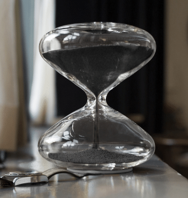 Hourglass black on a table with a watch